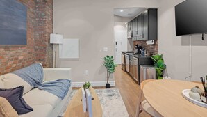 Ein modernes Wohnzimmer mit einer Ziegelfassade, einem Sofa, einem Couchtisch und einem an der Wand montierten Fernseher.