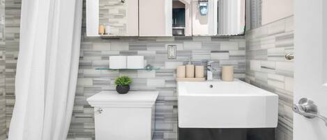 Een moderne badkamer met toilet, wastafel en douche.