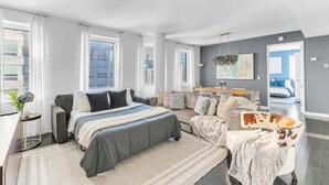 A modern bedroom with a large bed, a sofa, a chair, and a desk.