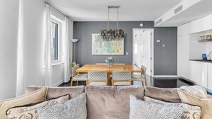 A modern dining area with a wooden table, cushioned chairs, and a hanging light fixture.