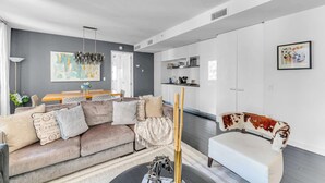 A modern living room with a sofa, a decorative horse sculpture, and a white chair.