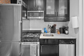 Una cocina equipada con un refrigerador de acero inoxidable, microondas, estufa y lavavajillas.