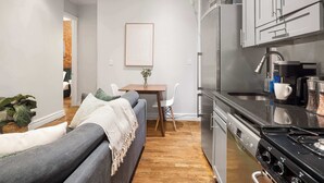 Una cocina moderna con electrodomésticos de acero inoxidable, un comedor con mesa y sillas, y una zona de estar acogedora con un sofá.
