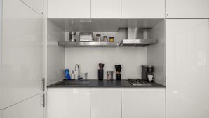 Une cuisine moderne avec des armoires blanches, des appareils en acier inoxydable et un comptoir noir.