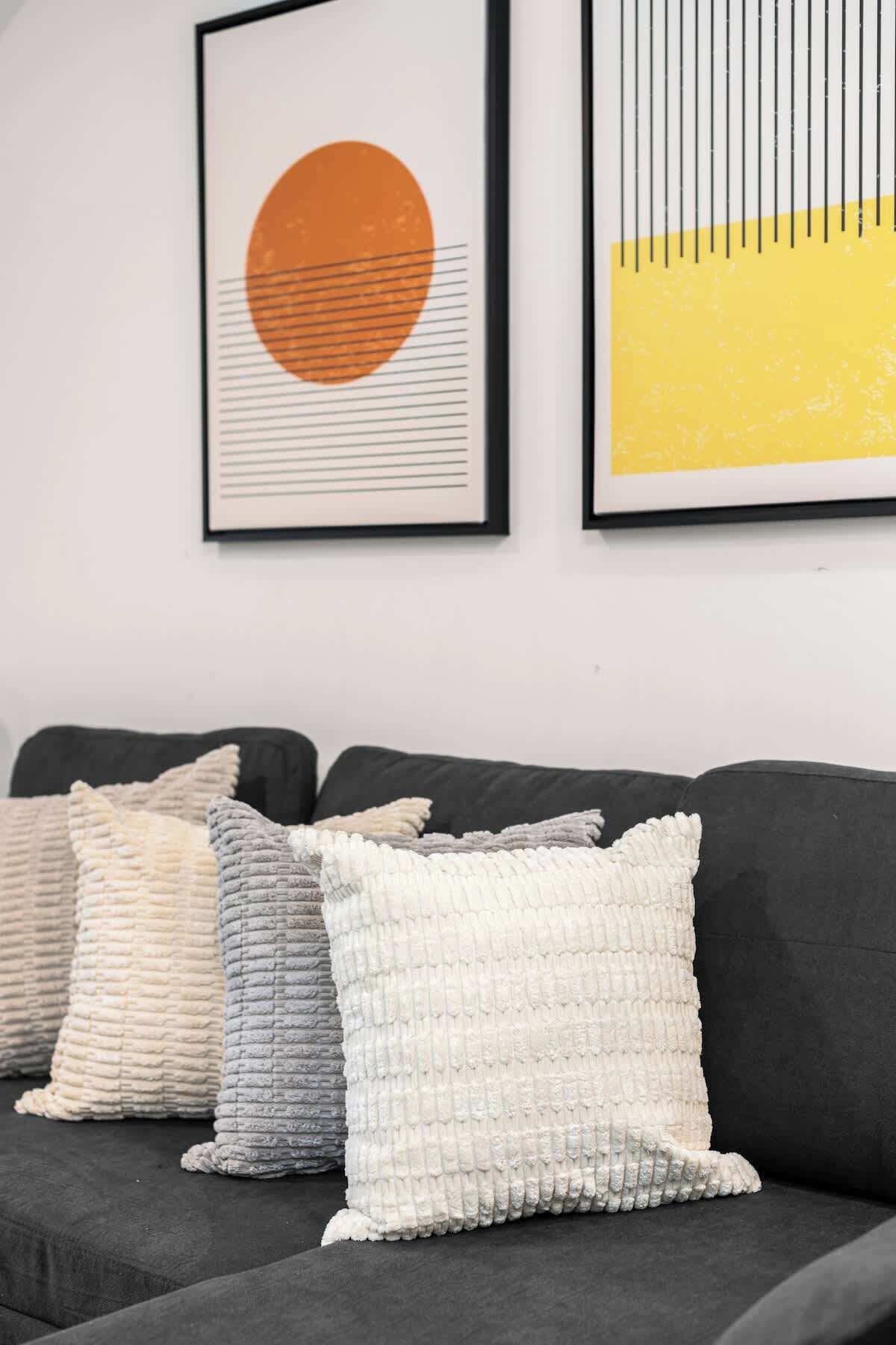 A dark grey sofa with several textured throw pillows in various colors.