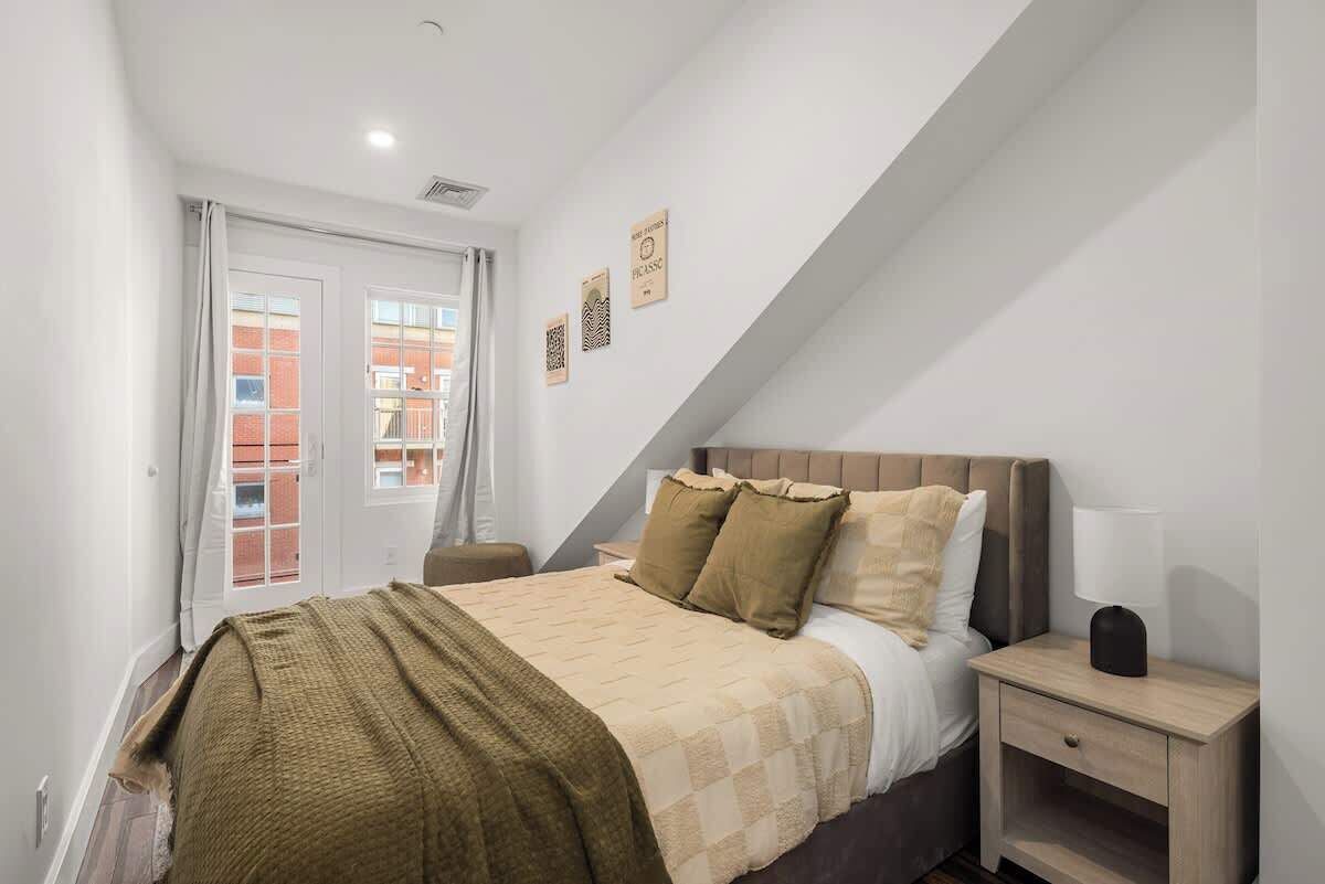 A bedroom with a bed, nightstand, and a window with curtains.