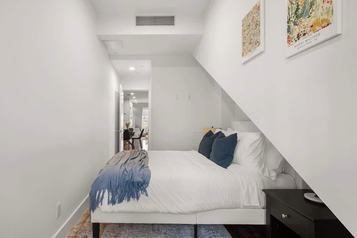 Une chambre moderne avec un lit, une table de chevet et une vue sur le couloir.