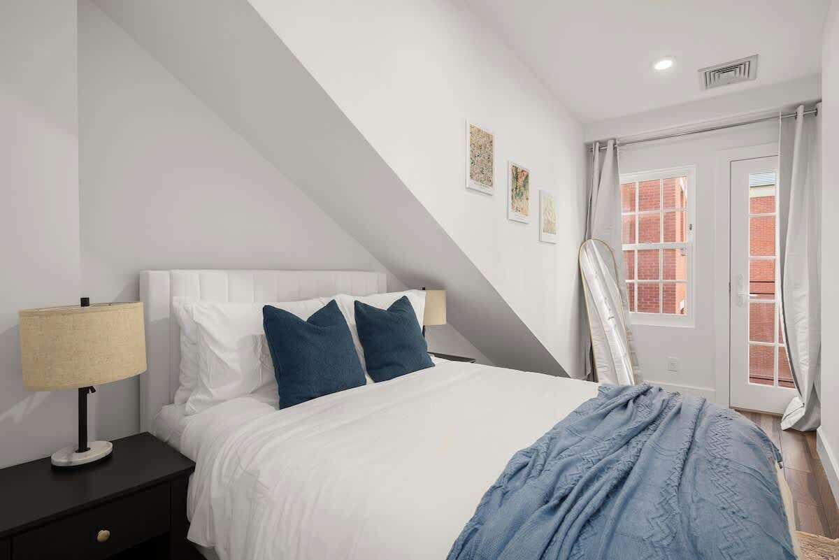 Una camera da letto con un letto, comodini, una lampada e una finestra con tende.