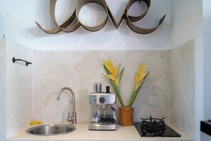 Een keuken met een spoelbak, koffiezetapparaat en fornuis.