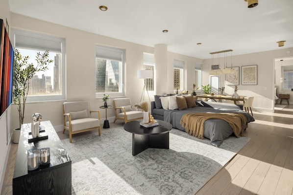 A spacious living room with a sofa, armchairs, a coffee table, and a dining area with a table and chairs.