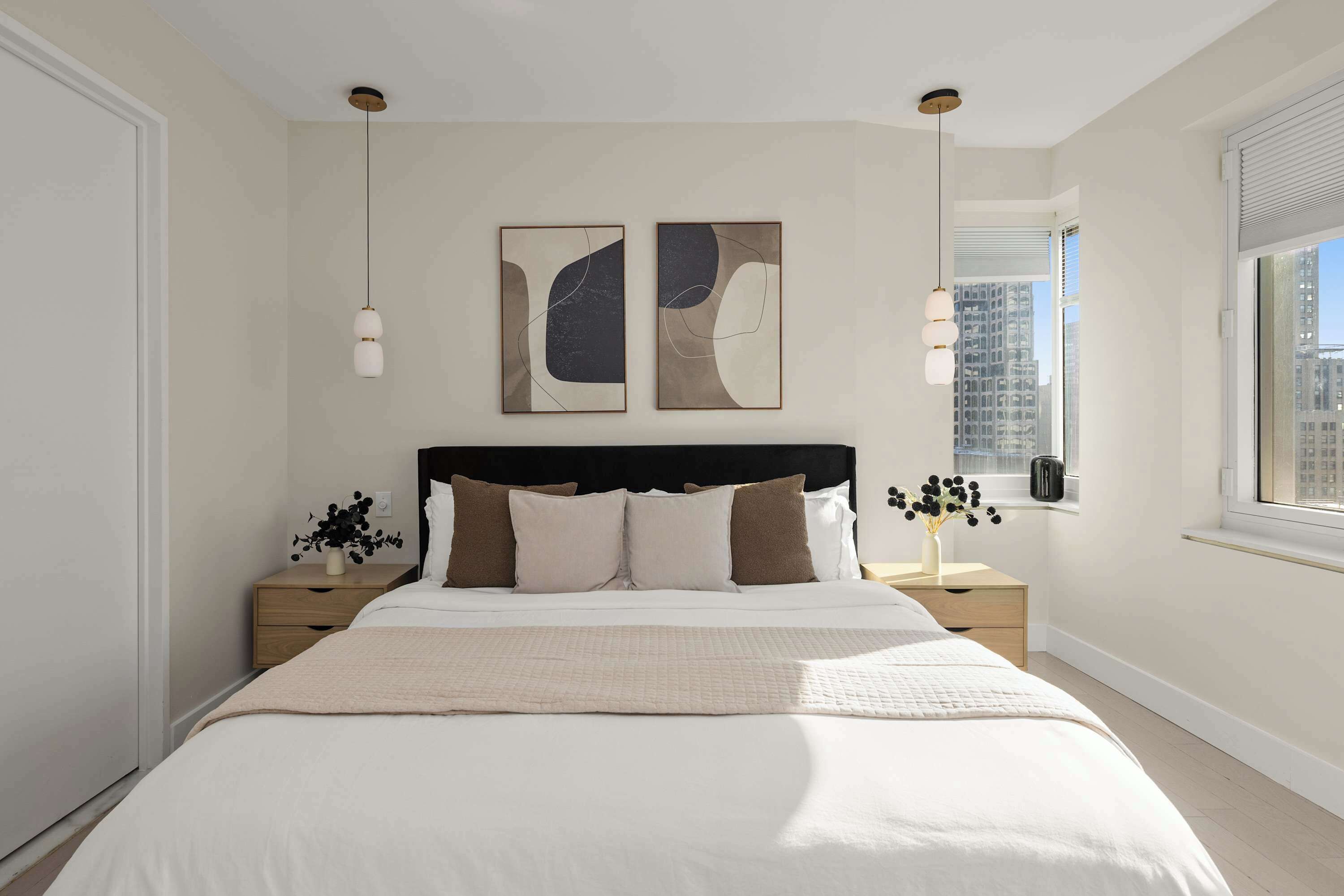 A modern bedroom with a large bed, two bedside tables, a headboard, and abstract wall art.