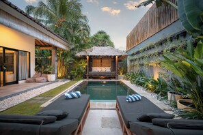 A poolside area with lounge chairs, a thatched-roof structure, and lush tropical plants. - 100m to Seminyak Beach / Personal Full-Time Butler (Seminyak)