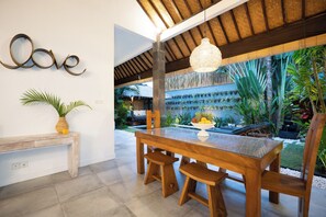 A wooden dining table with benches, a wall-mounted 'Love' sign, and a hanging light fixture. - 100m to Seminyak Beach / Personal Full-Time Butler (Seminyak)