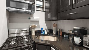 Une cuisine moderne dotée d’appareils électroménagers en acier inoxydable, d’un évier et de meubles de rangement aux couleurs sombres.