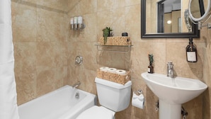 A bathroom with a bathtub, toilet, and sink. - Premier Midtown Stay | Walk to Times Square! (New York)