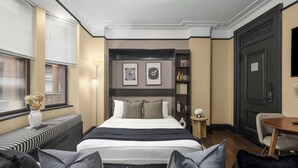 A modern hotel room with a large bed, a seating area with a bench, a small table, and a chair. - Premier Midtown Stay | Walk to Times Square! (New York)