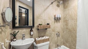 Une salle de bain équipée d’un lavabo, de toilettes et d’une baignoire, ainsi que d’un miroir et de produits de toilette rangés sur des étagères.