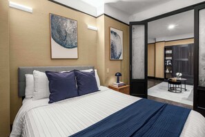 Una habitación de hotel con una cama grande, una mesita de noche, un escritorio y un armario.