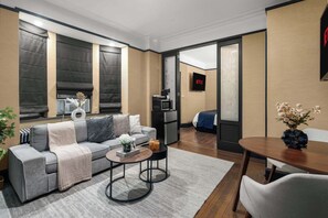 Una sala de estar moderna con un sofá gris, una mesa de centro y un comedor con mesa y sillas de madera.