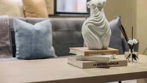 Un florero blanco sobre una mesa con libros y un pequeño florero con flores.