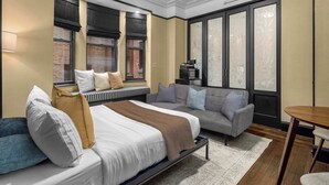 Una habitación de hotel moderna con una cama grande, un sofá, una mesita y un televisor.