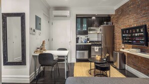 A compact kitchen with dark cabinets, a stainless steel refrigerator, and a microwave. - Chic 2BR Retreat in the Heart of Times Square (New York)