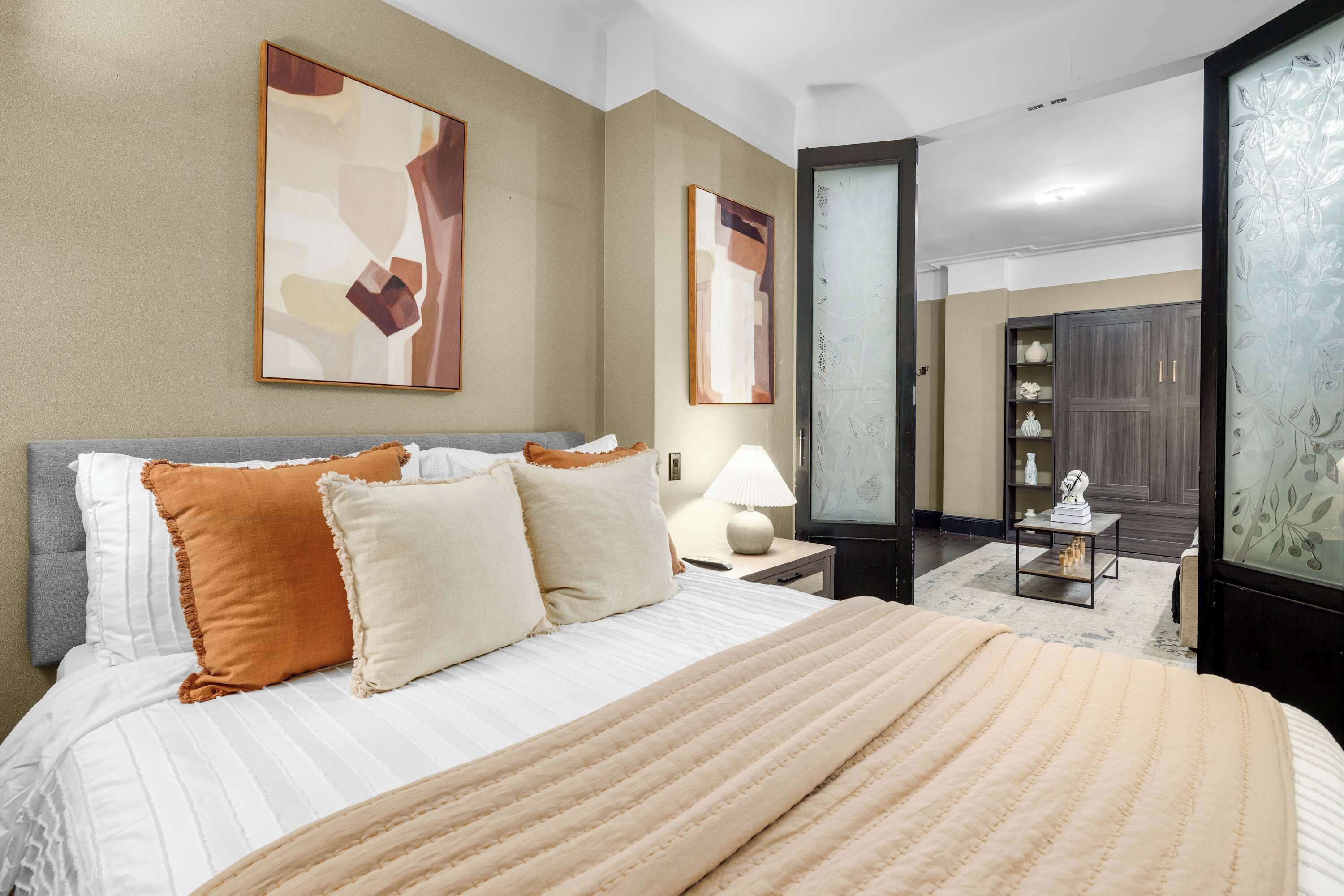A neatly arranged bedroom with a large bed, a bedside table with a lamp, and a wardrobe.