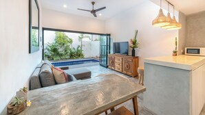 Una sala de estar moderna con piscina, televisor y comedor.