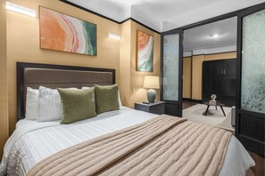 Une chambre d’hôtel avec un grand lit, une table de chevet, une lampe et une armoire.