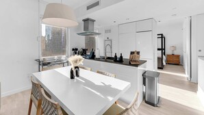 A modern kitchen with a large island, white cabinetry, and a view of the city. - One-Of-A-Kind 4 BR Duplex Steps from Time Square (New York)