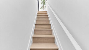 A wooden staircase with white walls and a view of a tree at the top. - One-Of-A-Kind 4 BR Duplex Steps from Time Square (New York)
