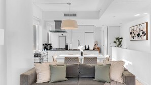 A modern living room with a grey sofa, a dining table, and a kitchen in the background. - One-Of-A-Kind 4 BR Duplex Steps from Time Square (New York)