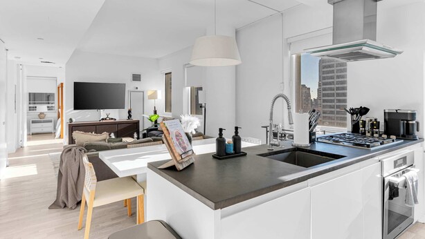 A modern kitchen with a central island, stainless steel appliances, and a large window offering a city view. - One-Of-A-Kind 4 BR Duplex Steps from Time Square (New York)