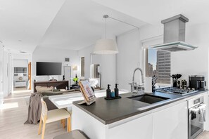 A modern kitchen with a central island, built-in appliances, and a large window.