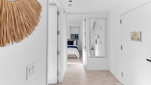 A hallway with a bed in the background, a wall-mounted mirror, and a door with a light switch. - One-Of-A-Kind 4 BR Duplex Steps from Time Square (New York)