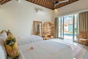 A bedroom with two beds, a wooden ceiling fan, a large mirror, and a view of a swimming pool through a glass door. - NEW Private Full-Time Butler / 7 Min Walk to Beach (Seminyak)