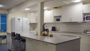 A modern kitchen with white cabinets, a central island with bar stools, a microwave, and a kettle. - Beautiful home in Flyinge with WiFi (Flyinge)