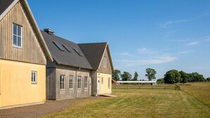 A large barn with a sloped roof and multiple windows, situated in a grassy field with a clear sky. - Beautiful home in Flyinge with WiFi (Flyinge)