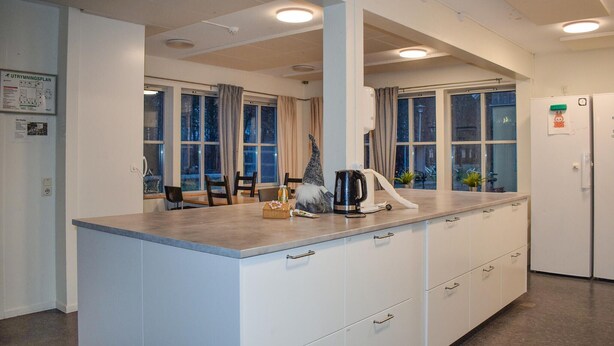 A modern kitchen with a large island, white cabinetry, and a view of the outdoors through large windows. - Beautiful home in Flyinge with WiFi (Flyinge)