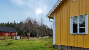 A yellow building with a white window and a red building in the background. - 3 bedroom beautiful home in Broaryd (broaryd)