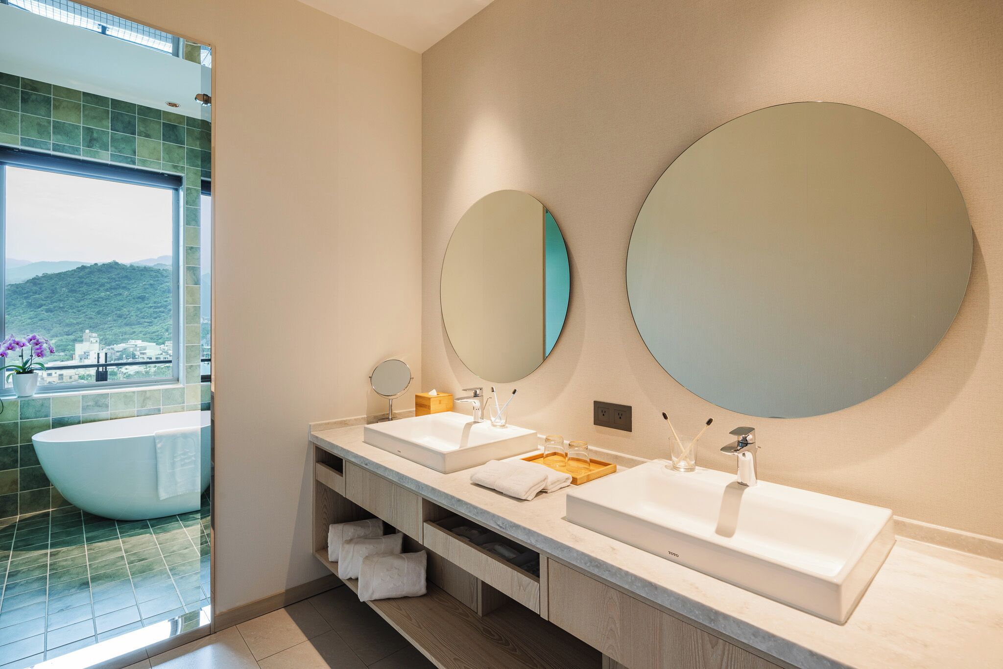 A modern bathroom with two sinks, a large mirror, and a bathtub.