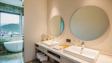 A modern bathroom with two sinks, a large mirror, and a bathtub.