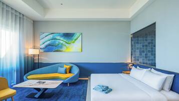 A hotel room with a bed, a sofa, a coffee table, and a painting on the wall.