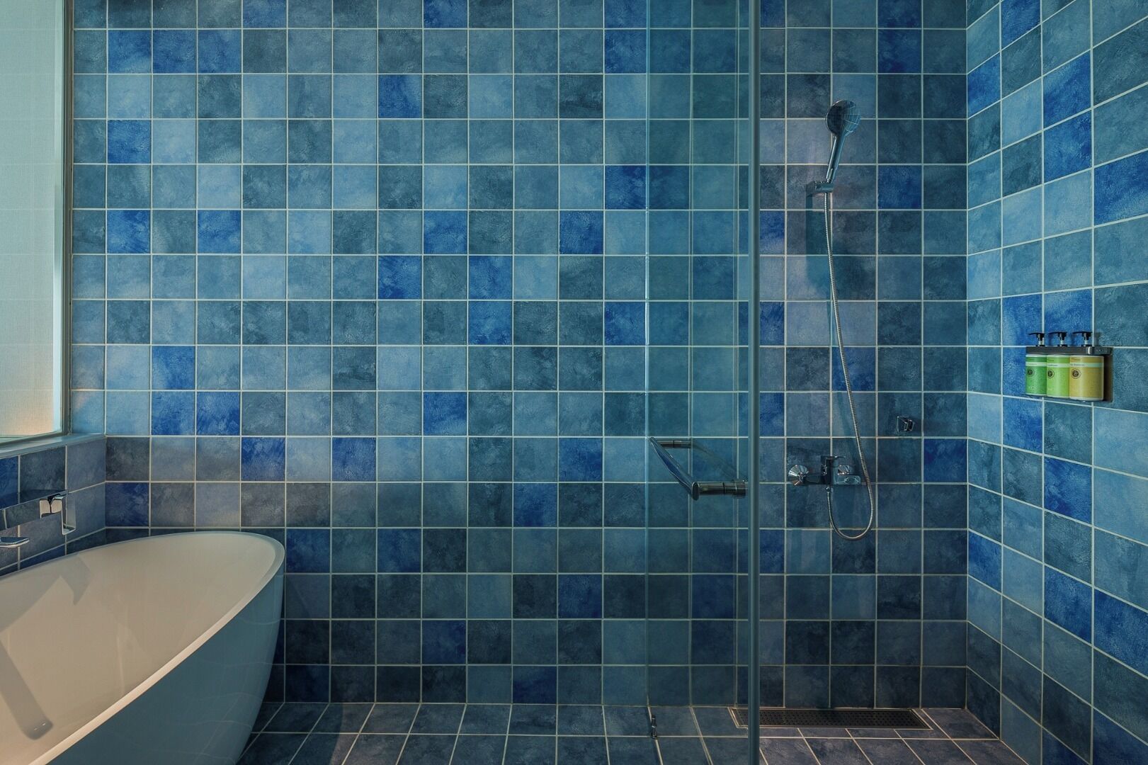 Un baño con bañera, ducha y paredes de azulejos azules.