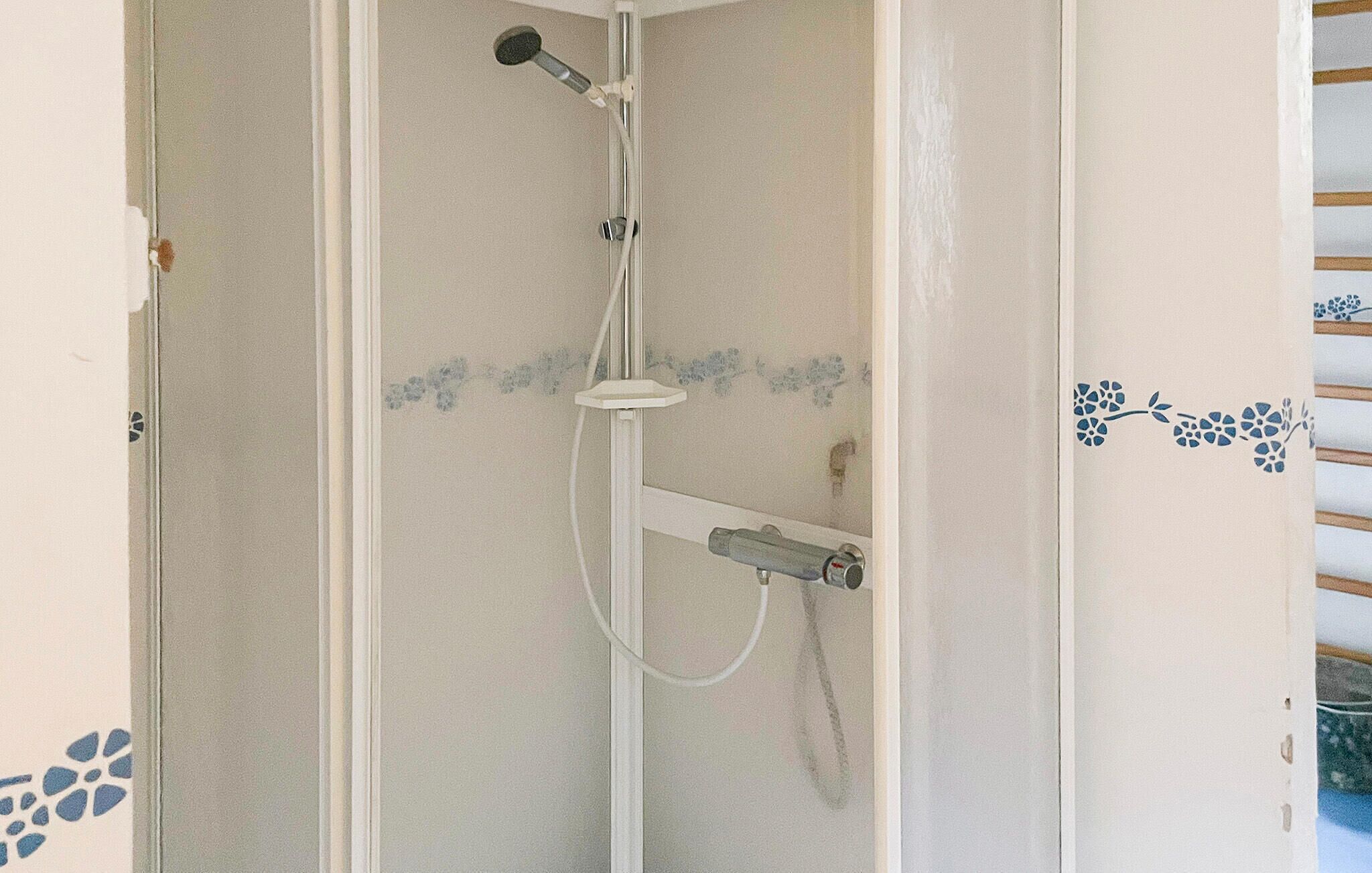 A shower enclosure with a handheld showerhead and a fixed showerhead.