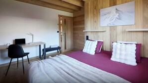 Ein Zimmer mit einem Bett, einem Schreibtisch, einem Sessel und einem Bild an der Wand.