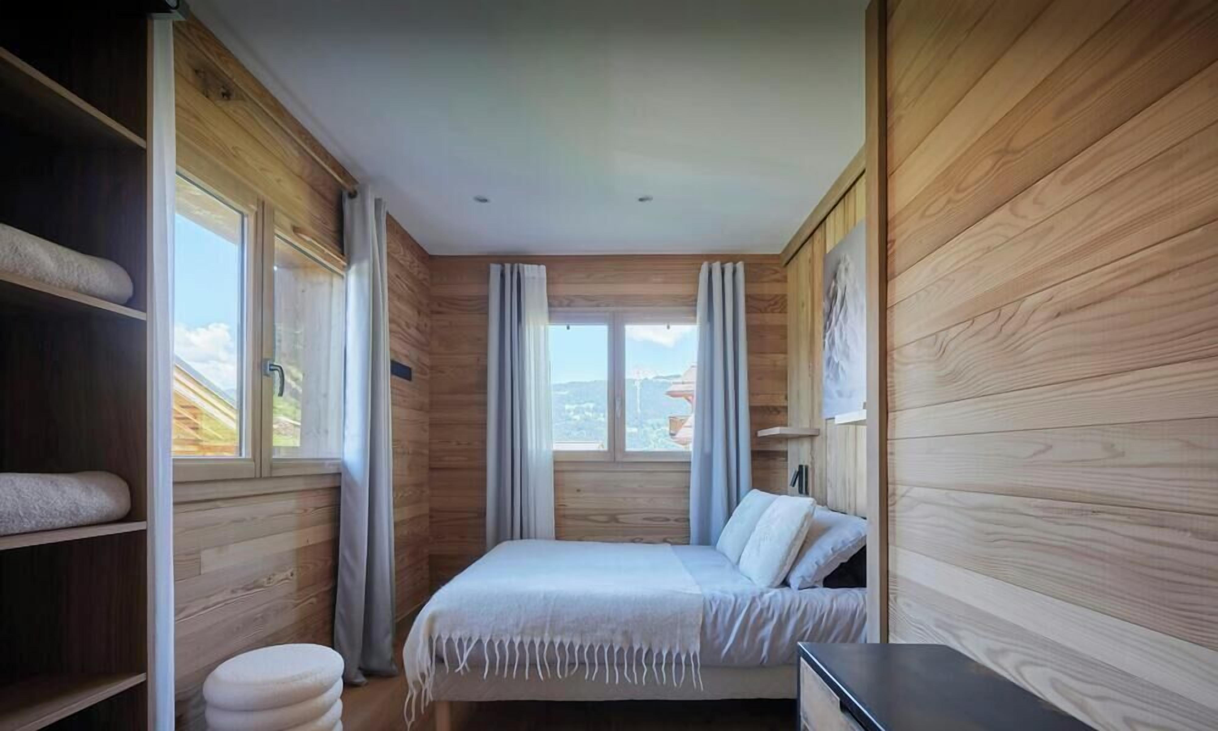 Ein Schlafzimmer mit Bett, Nachttisch, Kleiderschrank und einem Fenster mit Vorhängen.