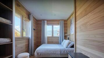 Ein Schlafzimmer mit Bett, Nachttisch, Kleiderschrank und einem Fenster mit Vorhängen.