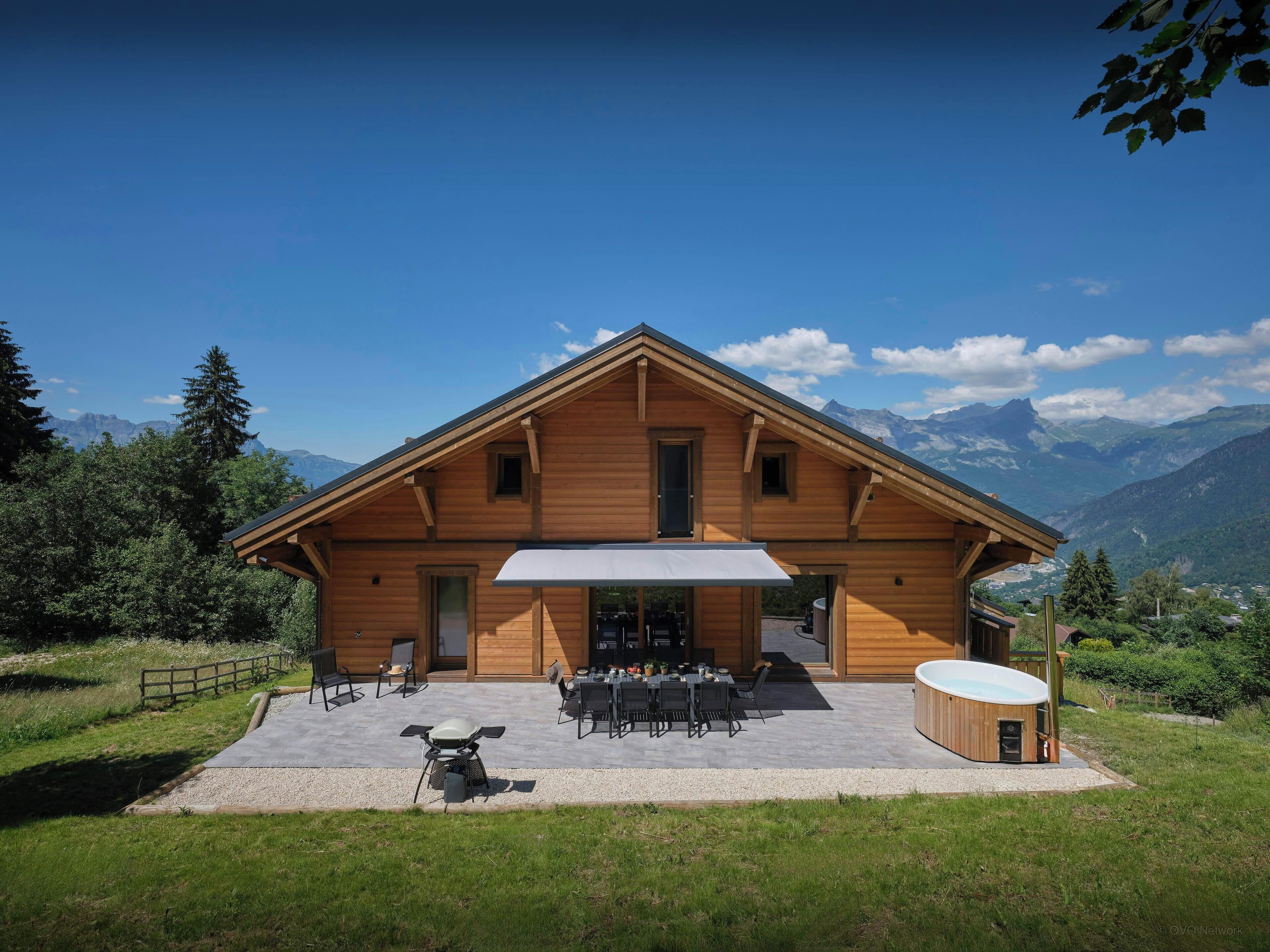 Un chalet en bois doté d’une terrasse, d’un espace salon extérieur et d’un jacuzzi.