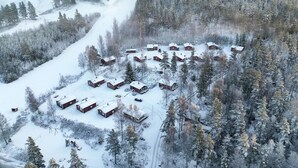 Um conjunto de cabanas de madeira em meio a uma floresta coberta de neve.